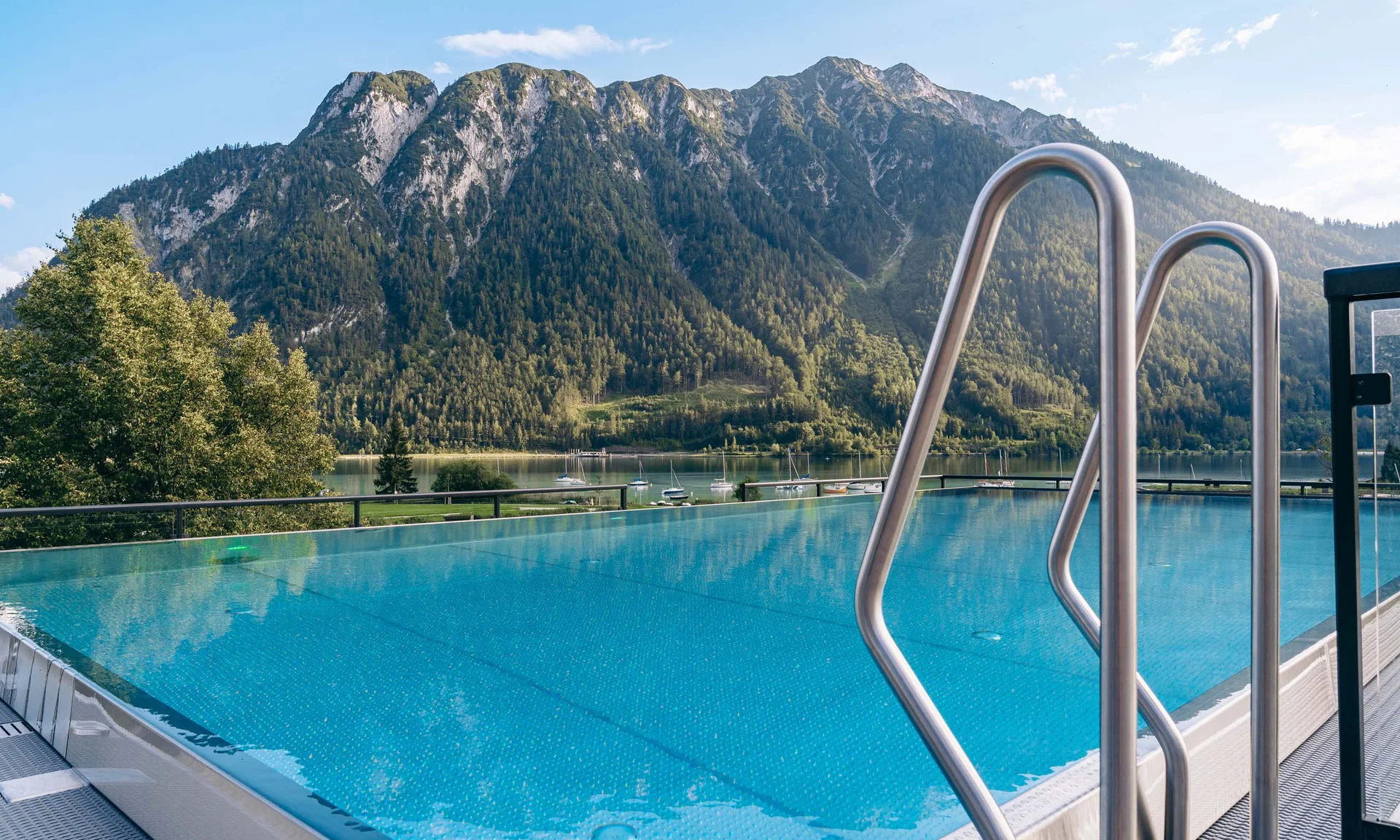 Wir lassen Bilder sprechen. Infinity-Pool mit Bergblick und See im Hintergrund bei sonnigem Wetter