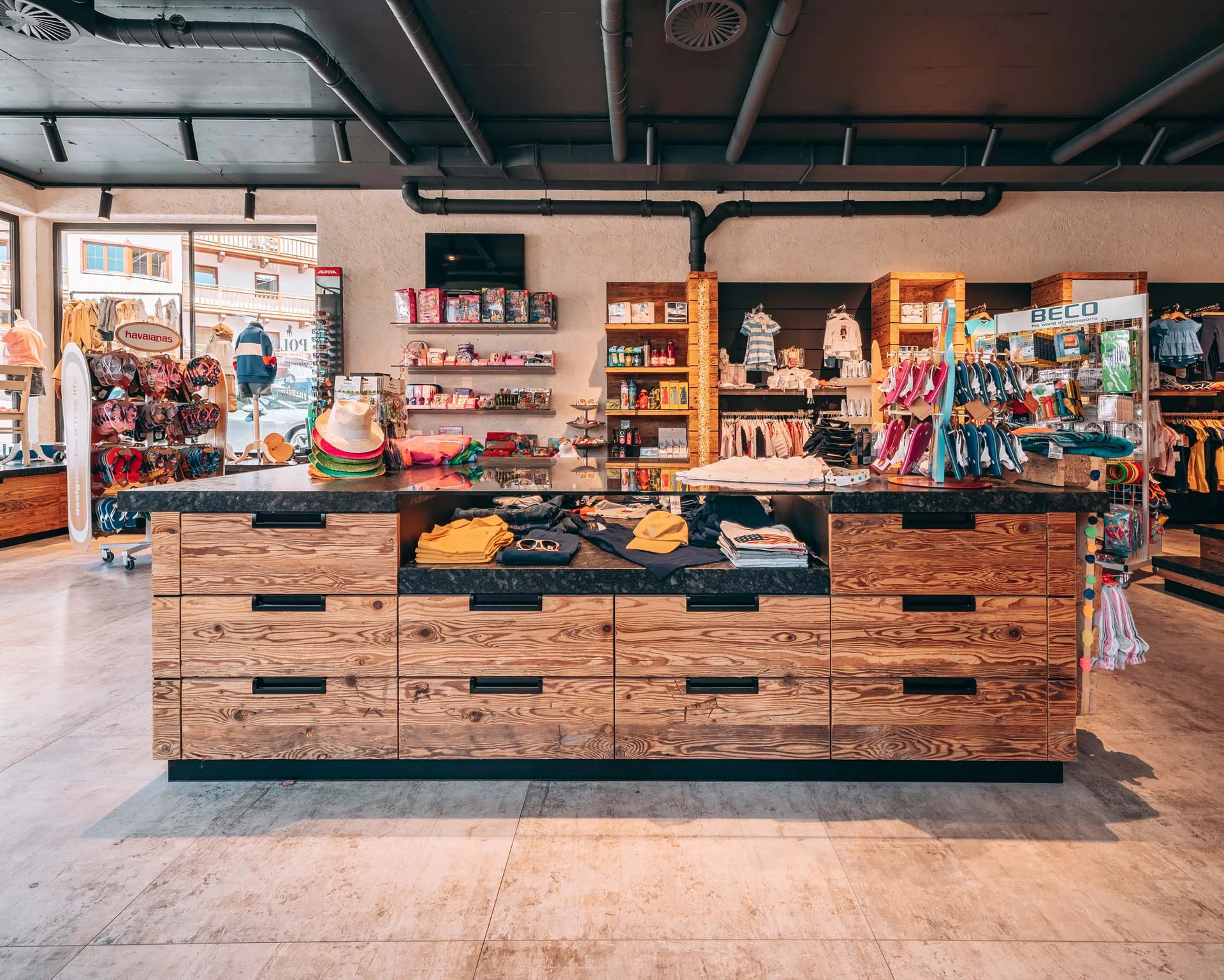 Familienzeit im Kinderhotel Buchau am Achensee Innenansicht eines Bekleidungsgeschäfts mit Holztheke und Regalen voller Kleidung und Accessoires