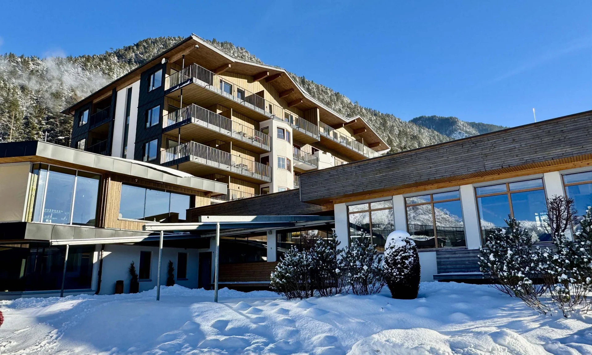 Wir lassen Bilder sprechen. Moderne Unterkunft im Schnee mit Bergen und klarem blauem Himmel im Hintergrund