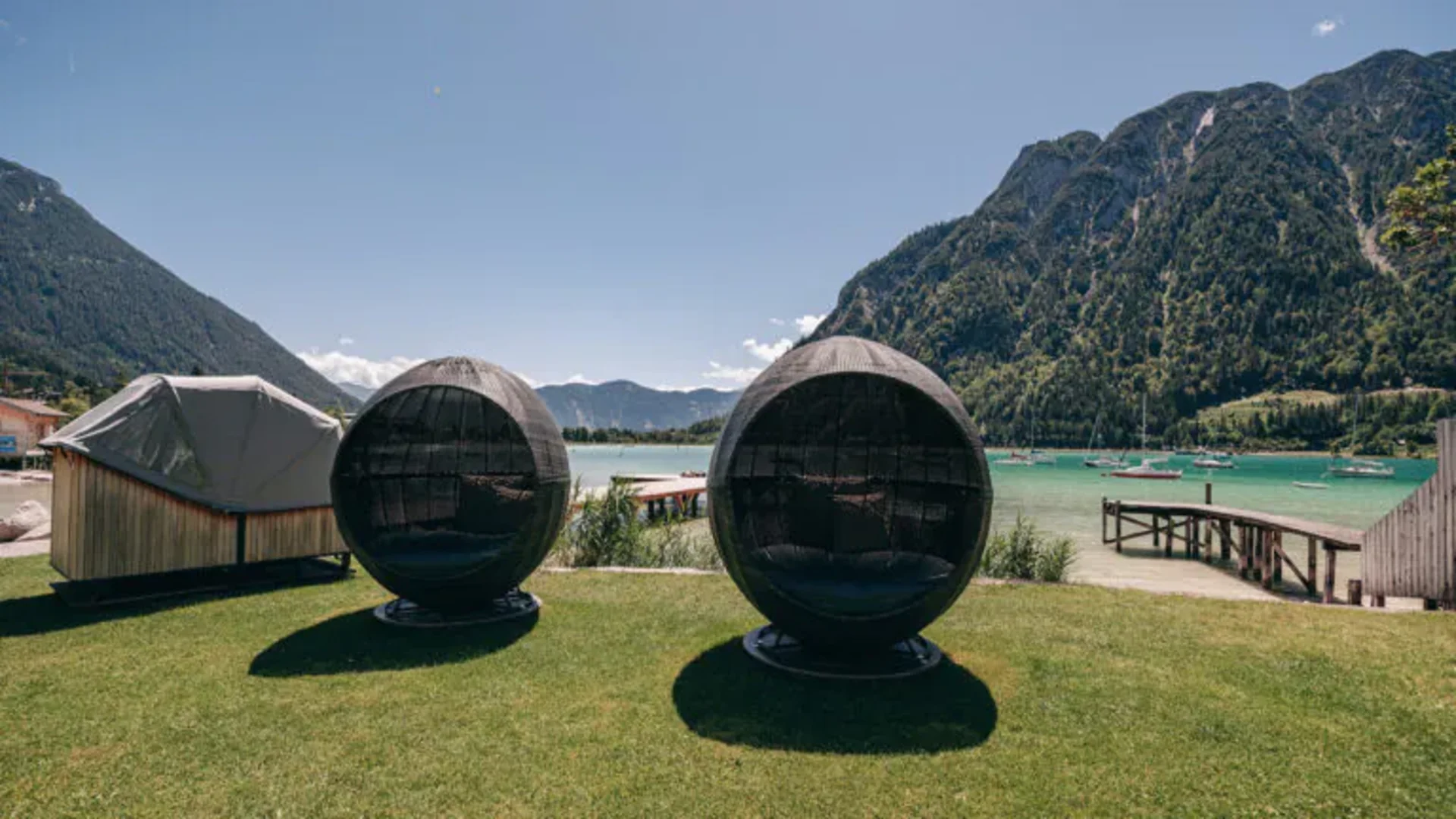 Wassersport auf dem See in Österreich Zwei runde schwarze Gartenstühle mit Blick auf See und Berge