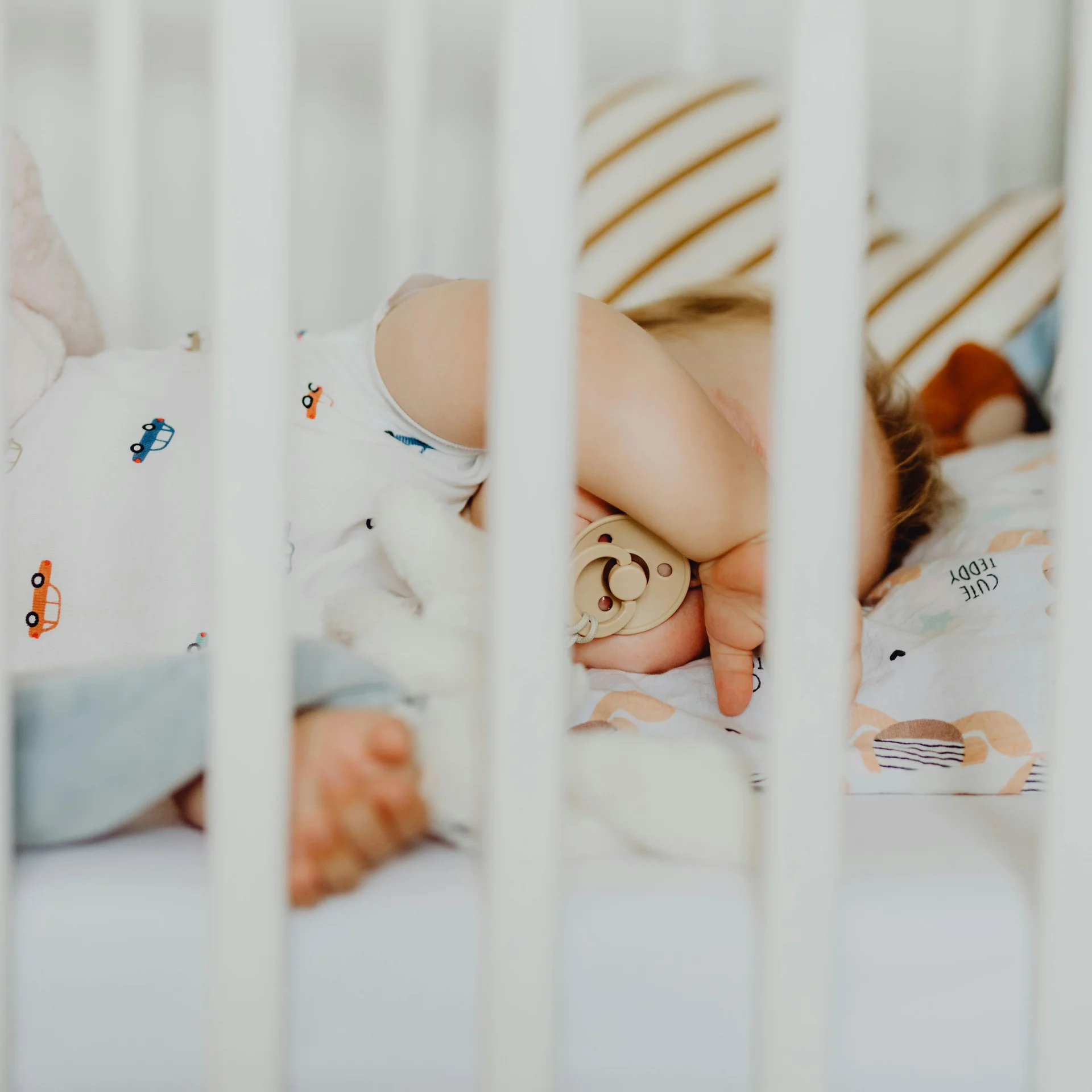 Familienurlaub mit Baby und Kleinkind im Buchau Schlafendes Baby mit Schnuller in einem Kinderbett mit weißen Gittern