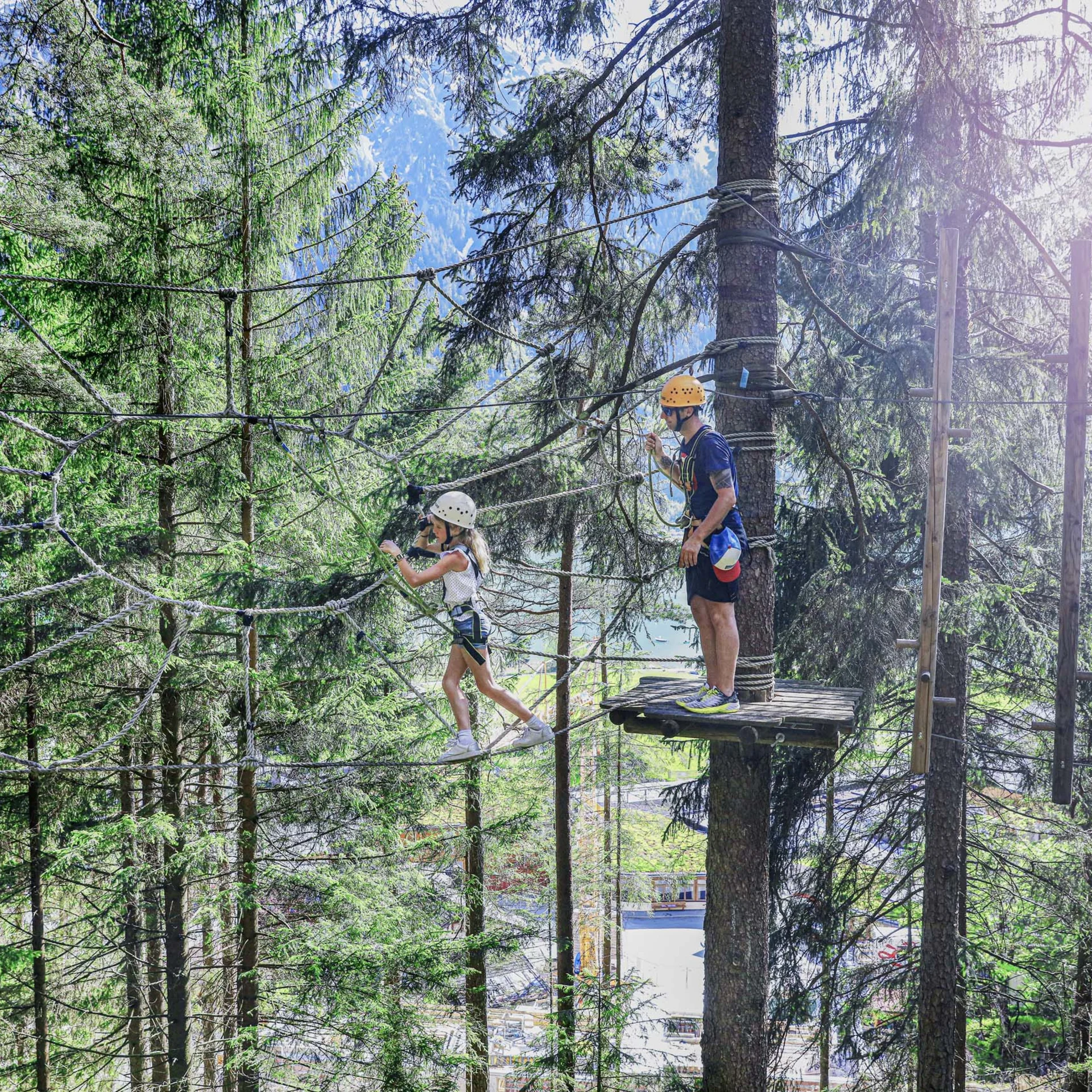 Familienzeit im Kinderhotel Buchau am Achensee Kind und Erwachsener beim Klettern in Hochseilgarten im Wald