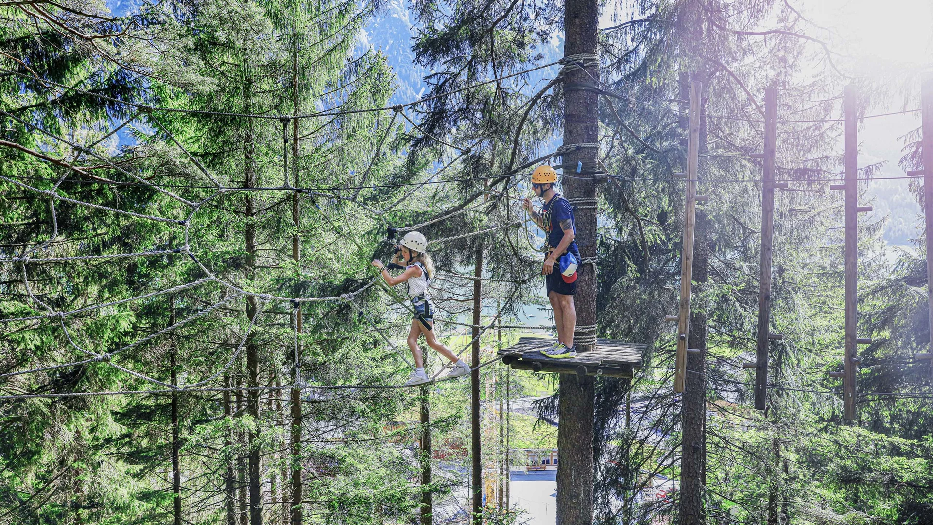 Ihr abenteuerlicher Erlebnisurlaub in Österreich Kind und Erwachsener beim Klettern in Hochseilgarten im Wald