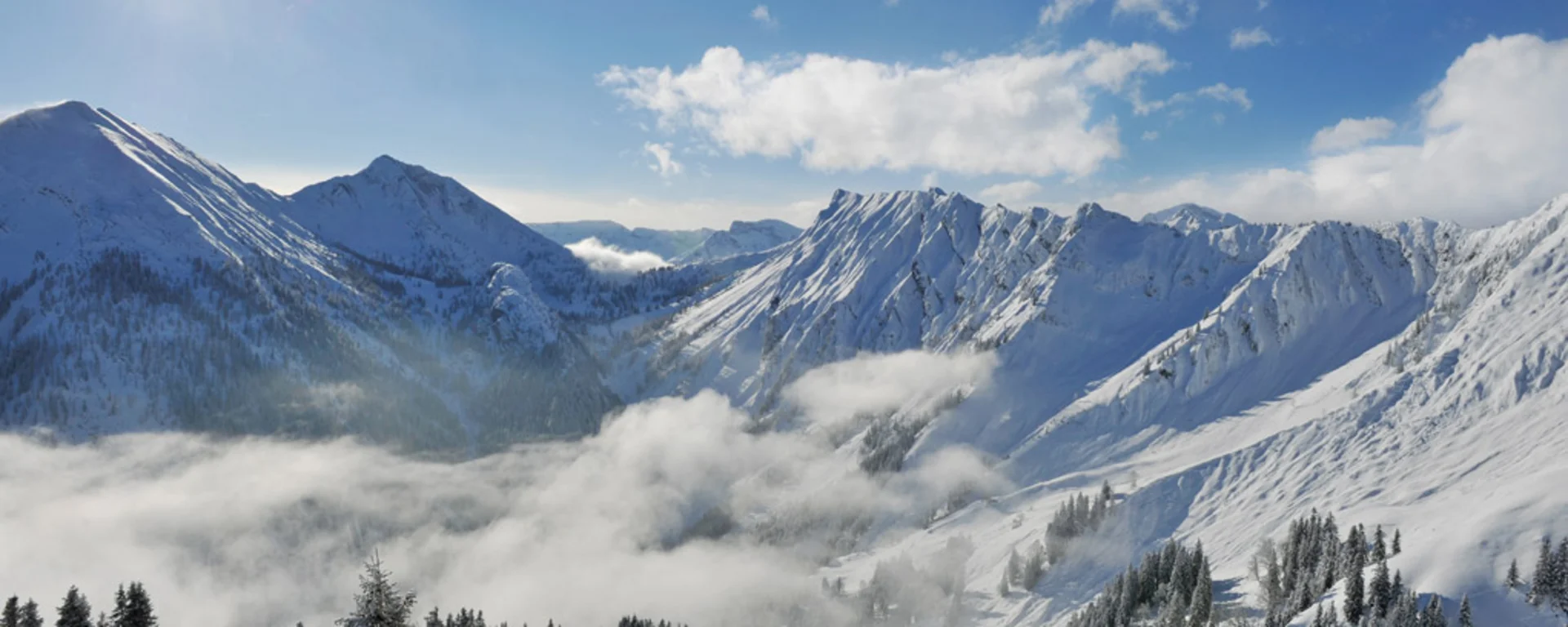 Urlaub im Familienresort in Österreich Sonnige, schneebedeckte Alpen mit Bergen, Wolken und Tannenbäumen