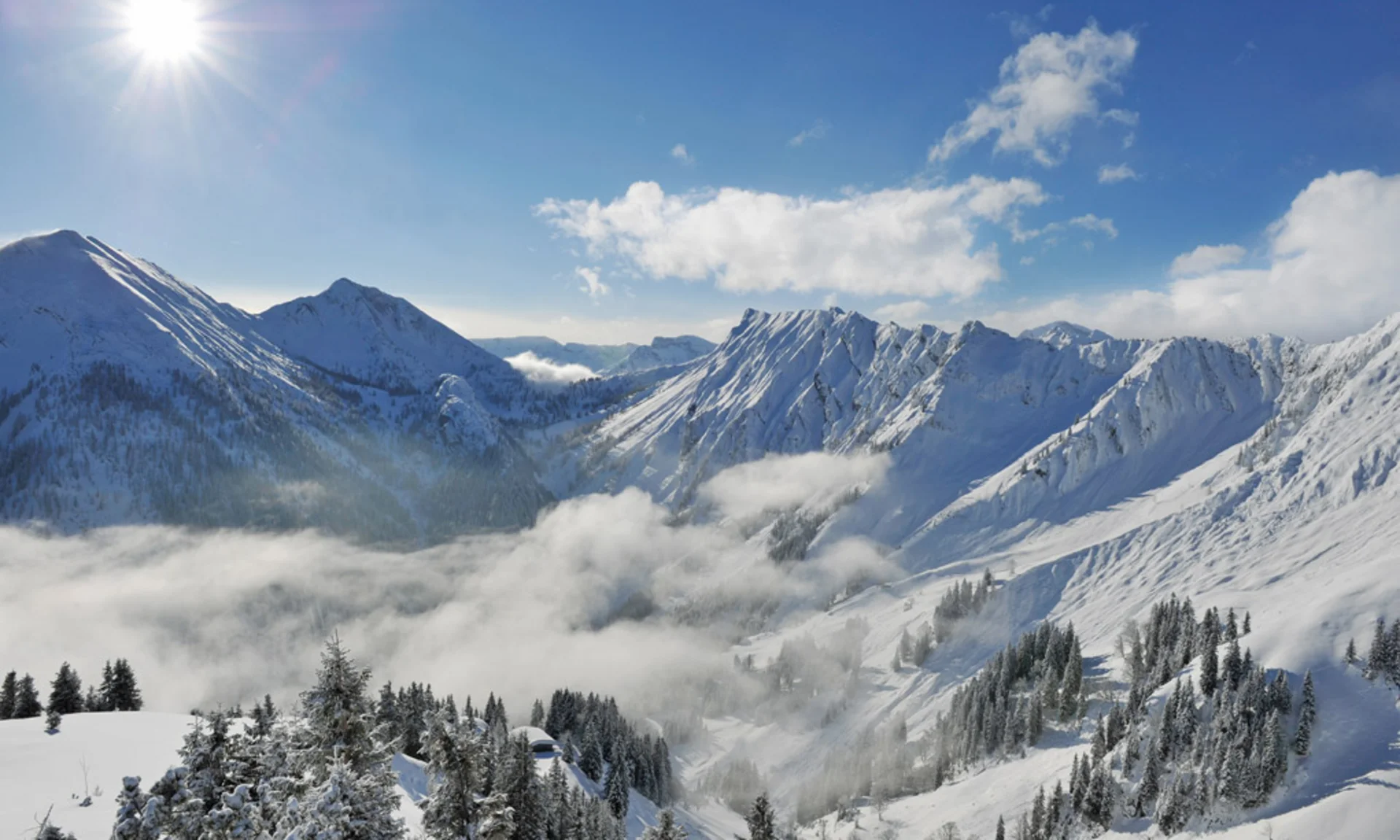 Your unforgettable active lakeside holiday in Austria Sunny snow-covered Alps with mountains, clouds, and pine trees