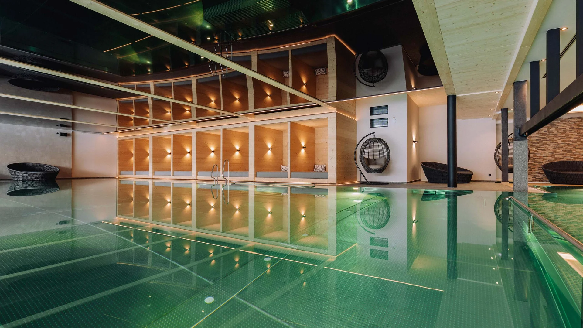 Wasserspaß im Familienhotel in Tirol mit Pool Moderner Innenpool mit gemütlichen Sitzbereichen und hängenden Korbstühlen