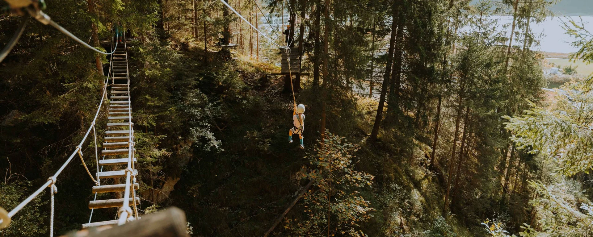 Aktiver Urlaub im Hotel mit Fußballcamp Kind fährt auf einer Seilrutsche durch einen Wald