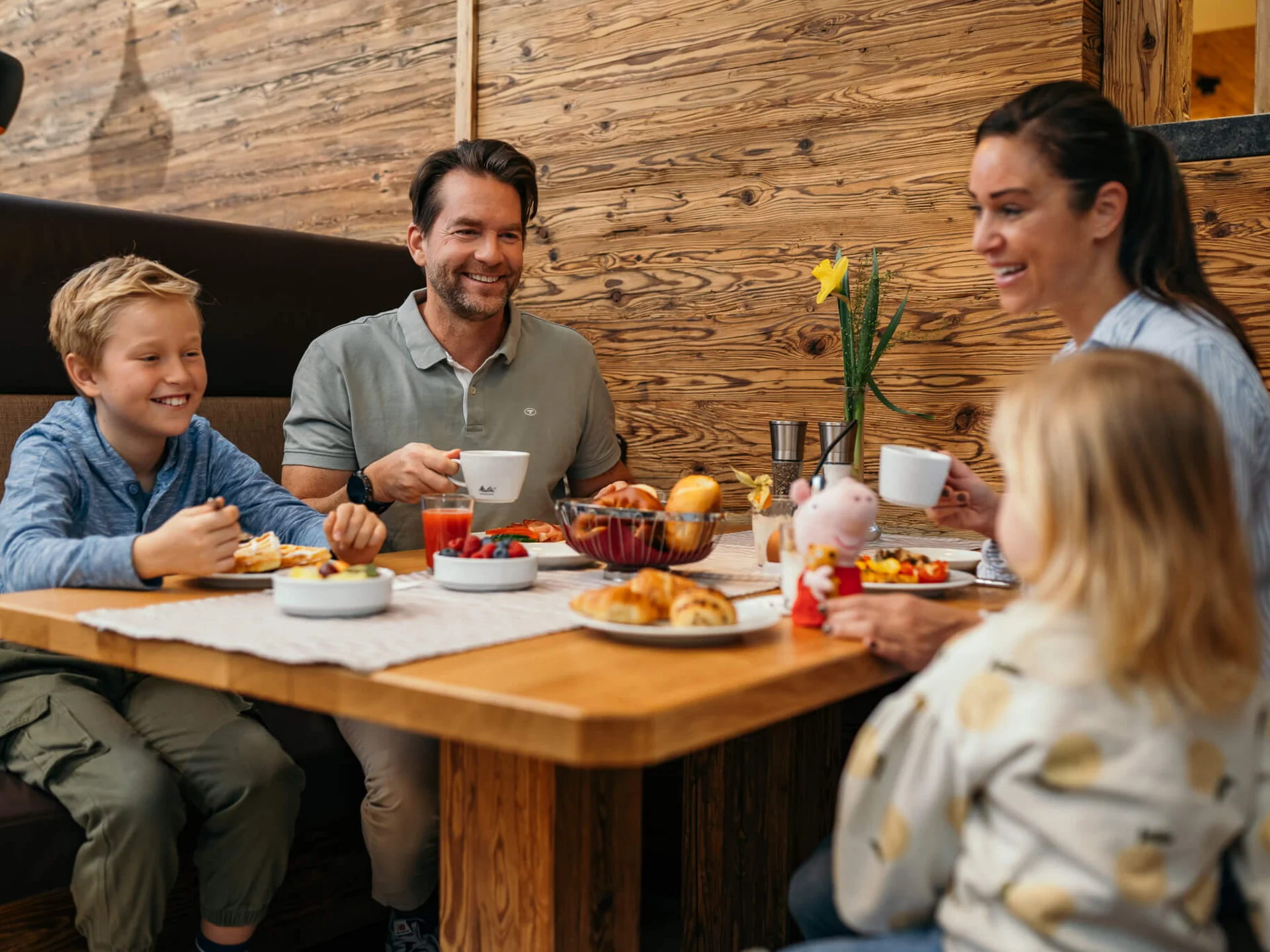 Ihr Familienhotel in Österreich mit All-inclusive-Angebot Familie mit zwei Kindern isst Frühstück an Holztisch in gemütlichem Restaurant
