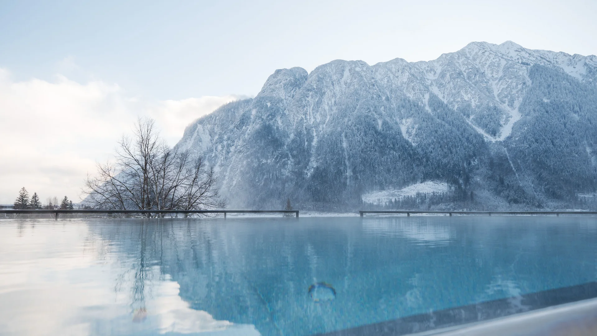 Wasserspaß im Familienhotel in Tirol mit Pool Infinity-Pool mit Blick auf schneebedeckte Berge und Nebel im Winter