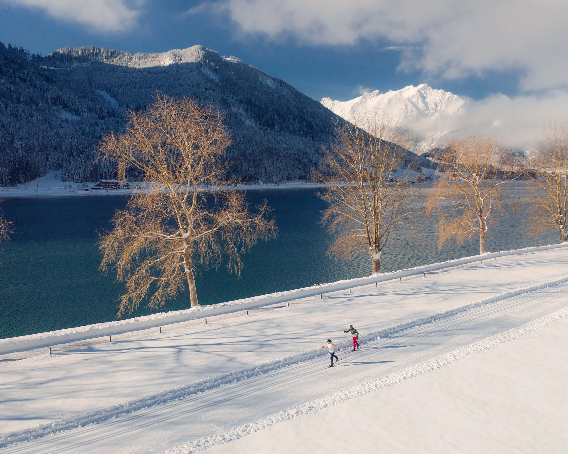 Erholungsurlaub für Eltern Langläufer auf verschneitem Pfad am See mit Bergen im Hintergrund