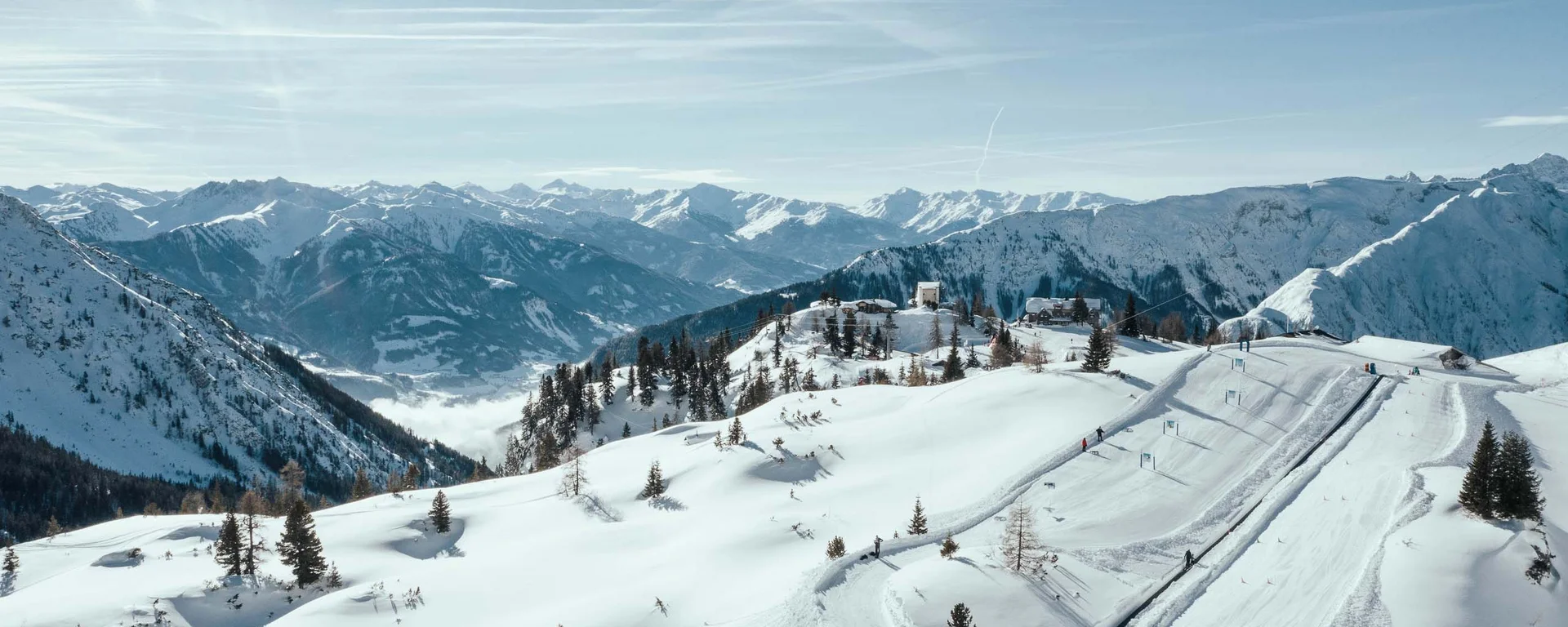 Der Wintertraum im Familien-Skihotel in Österreich Verschneite Alpenlandschaft mit Skigebiet und klarem Himmel
