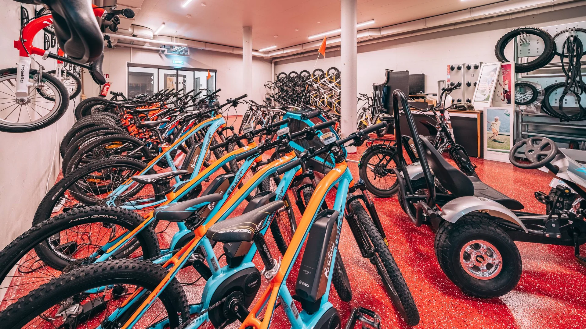 Vom Wanderhotel in Tirol direkt in die Natur Mehrere Elektrofahrräder und ein Go-Kart in einem hellen Raum abgestellt