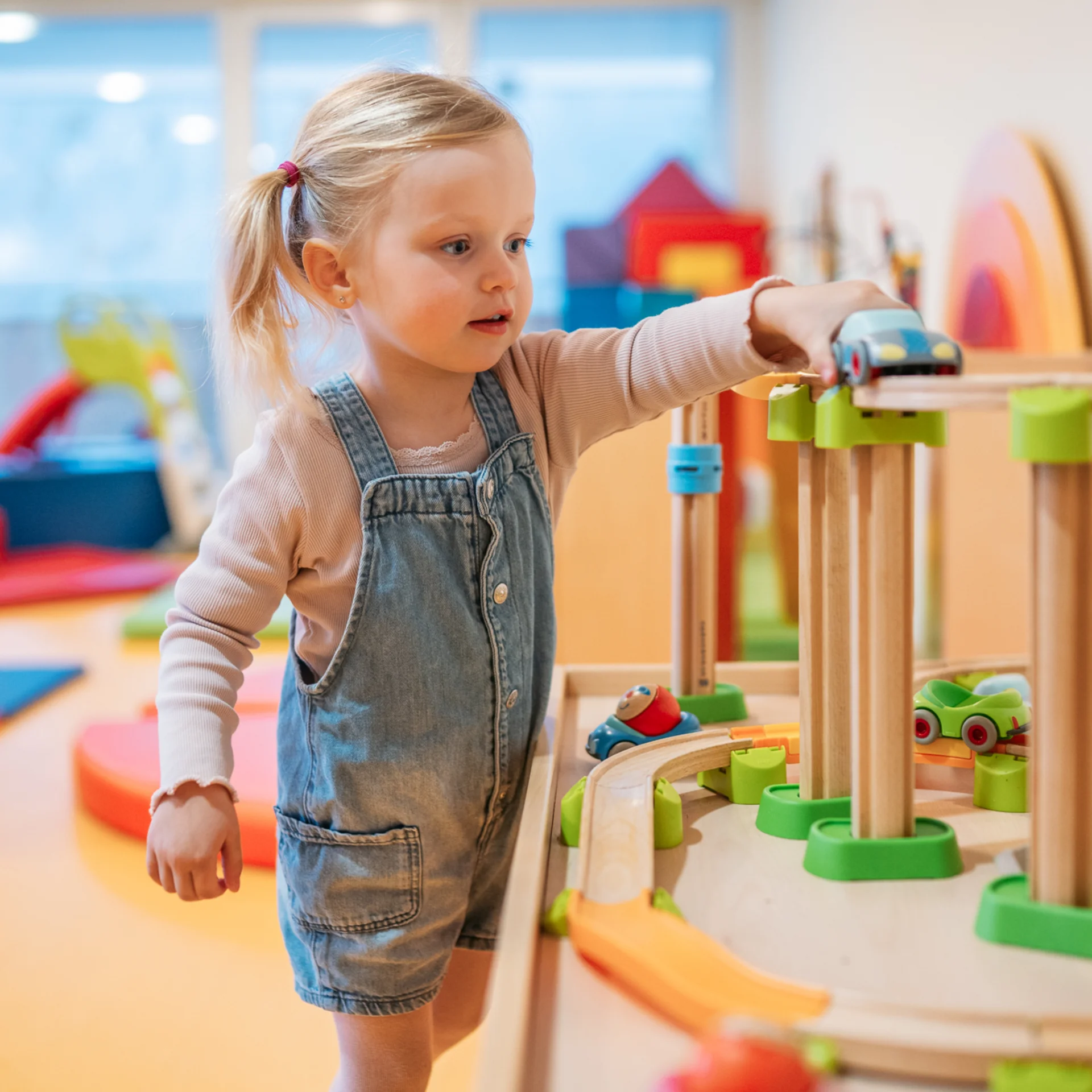 Familienzeit im Kinderhotel Buchau am Achensee Kleines Mädchen spielt mit einer Holzeisenbahn im Spielzimmer