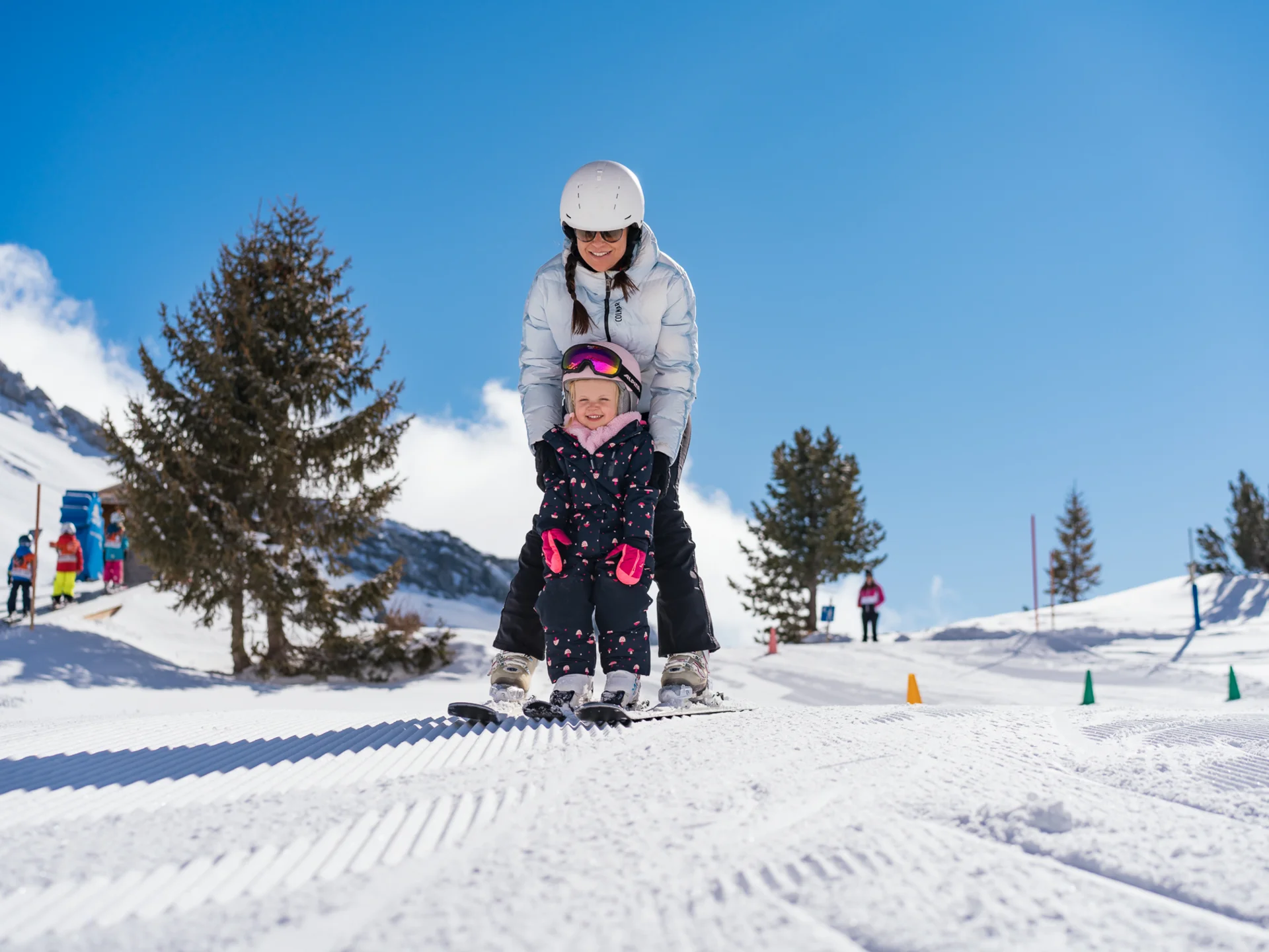 Der Wintertraum im Familien-Skihotel in Österreich Erwachsene und Kind lernen gemeinsam Skifahren auf verschneiter Piste bei sonnigem Wetter