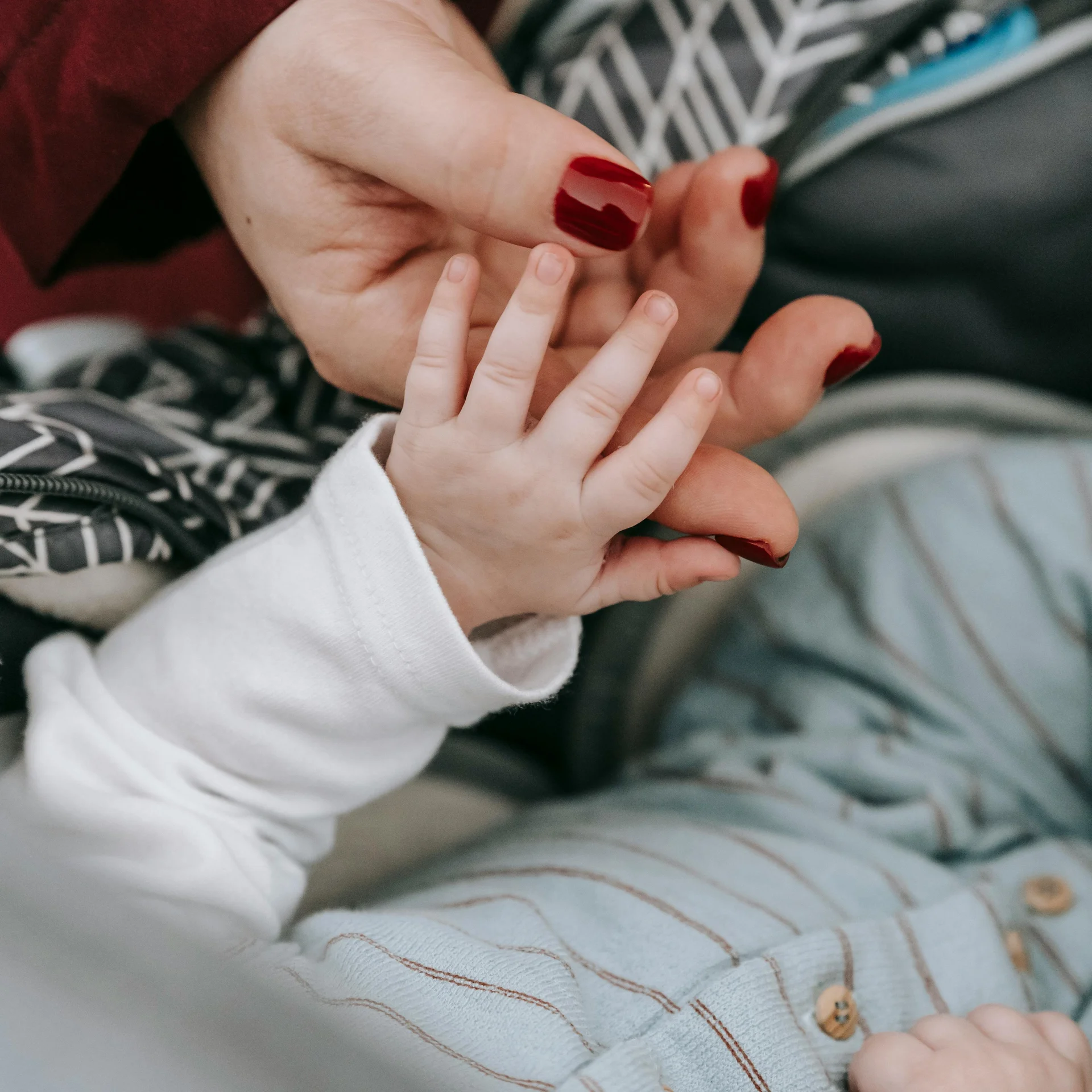 Familienurlaub mit Baby und Kleinkind im Buchau Erwachsen hand hält Babyhand mit rotem Nagellack