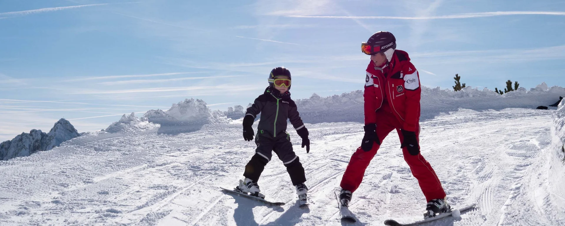 Outdoorspaß im Familienhotel am See in Österreich Kind und Skilehrer beim Skifahren auf verschneiter Piste bei Sonnenschein