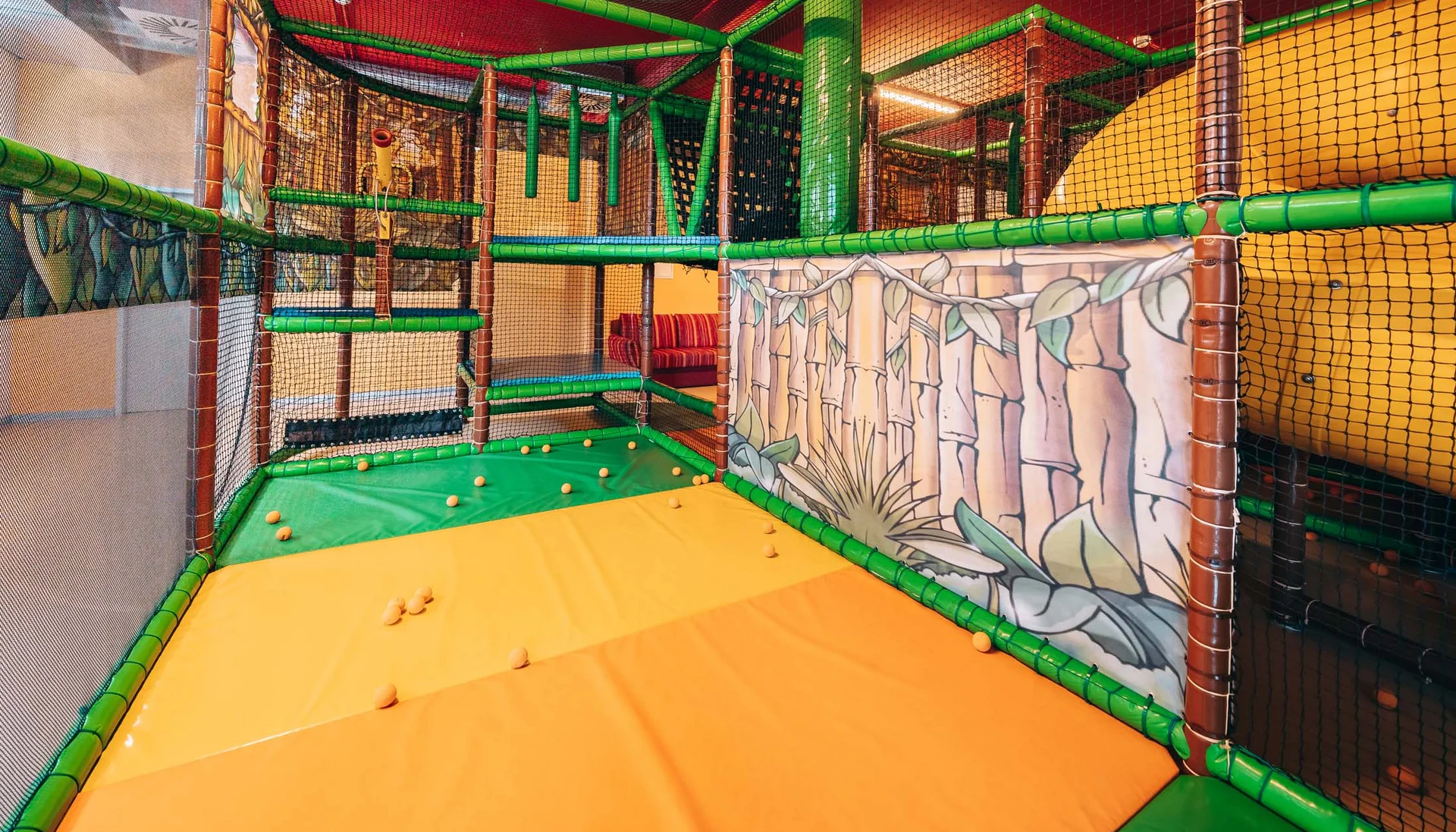 Ihr Hotel mit Kinderbetreuung in Tirol Innenraum eines bunten Indoor-Spielplatzes mit Klettermöglichkeiten und weichen Matten