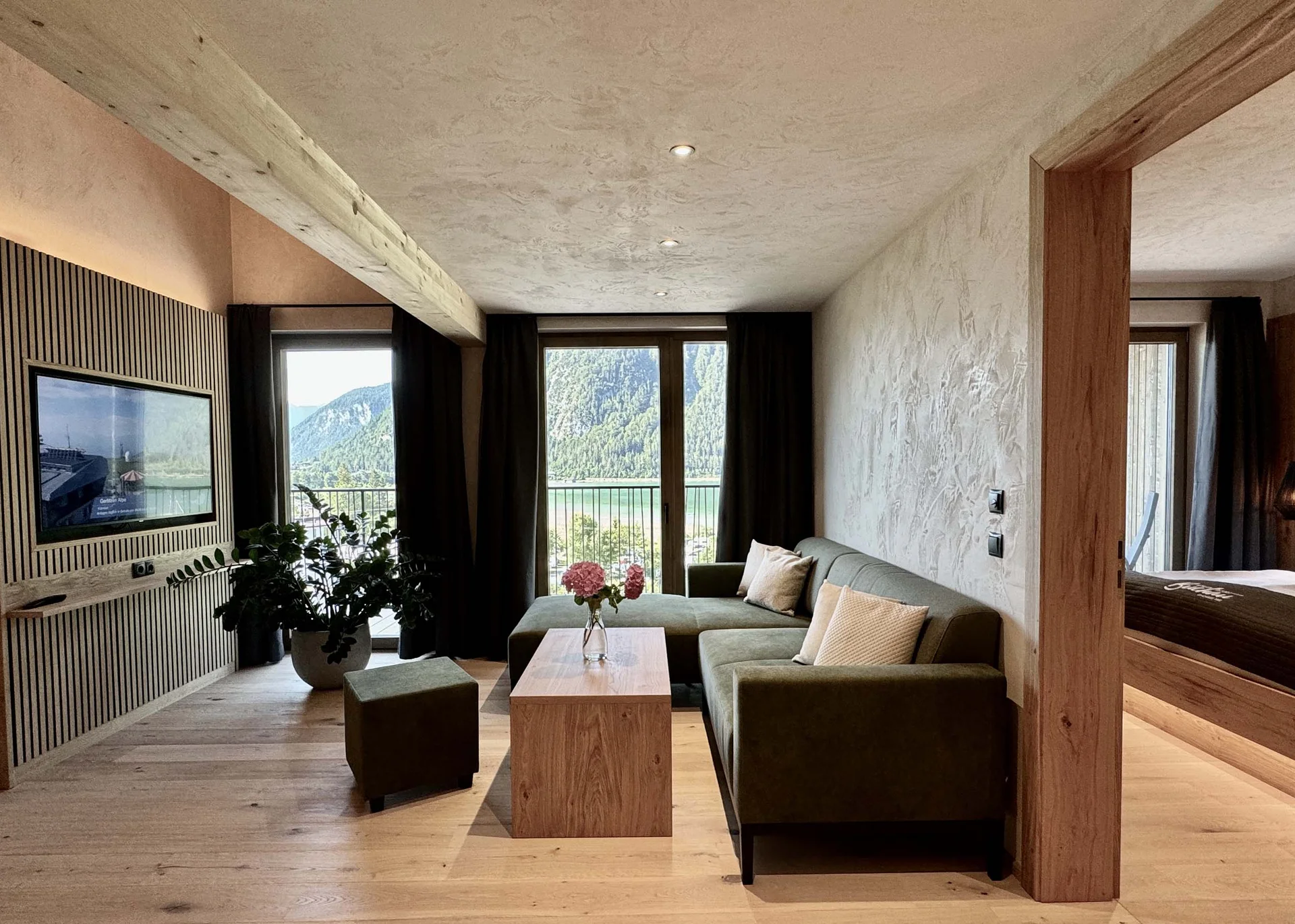 Zimmer und Angebote am Achensee Moderne Wohnung mit grünem Sofa, Holztisch und Balkon mit Bergblick
