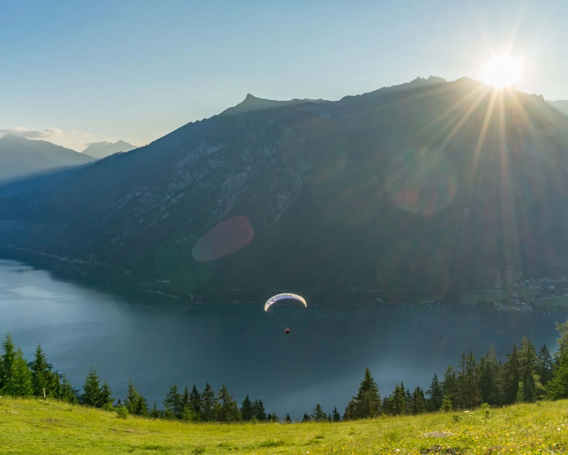 Ihr Rückzugsort in der Unterkunft am Achensee Paraglider fliegt über See mit Bergen und Sonnenuntergang im Hintergrund