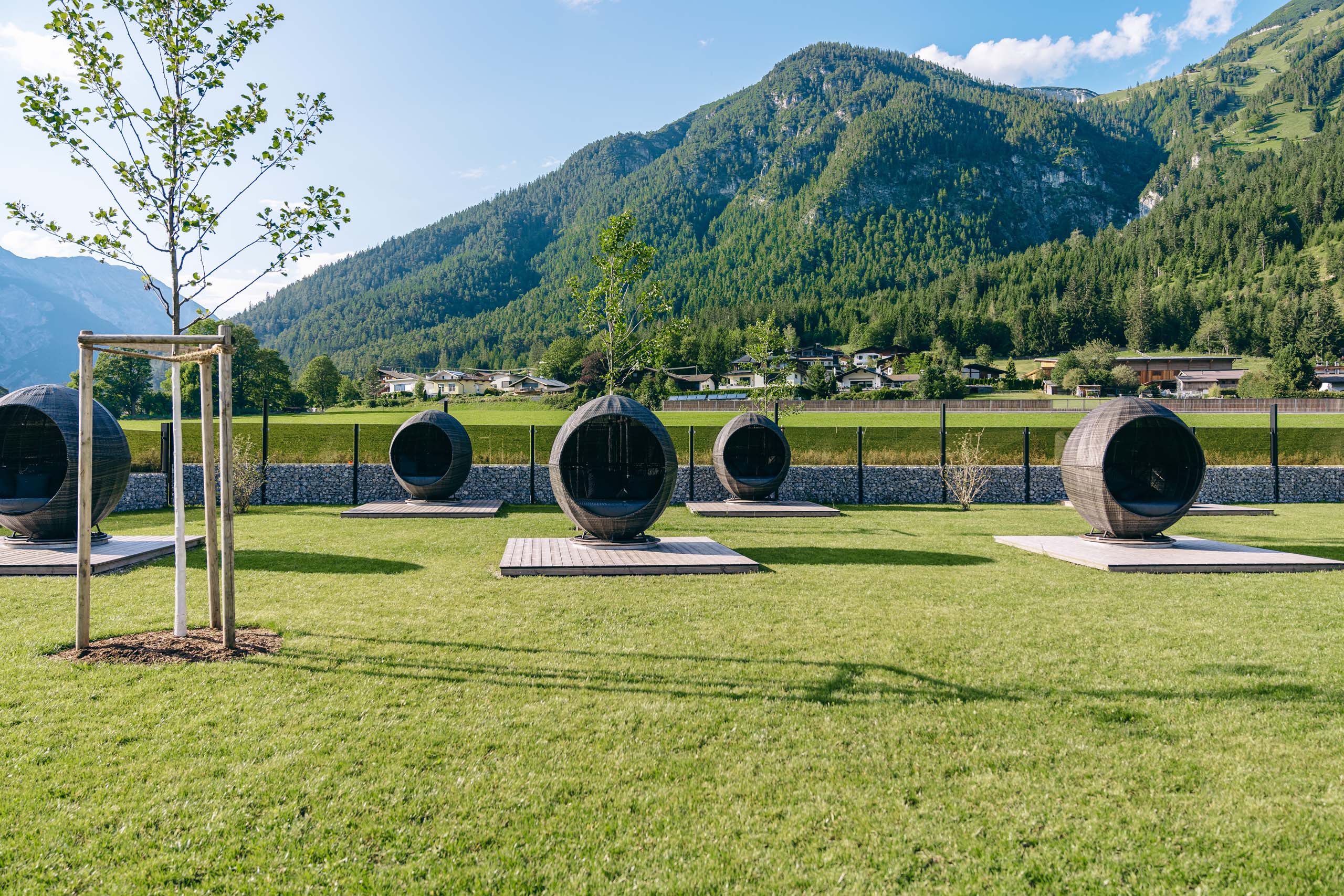 Wassersport auf dem See in Österreich Freizeitkapseln auf Rasenfläche vor bewaldeten Bergen und Häusern