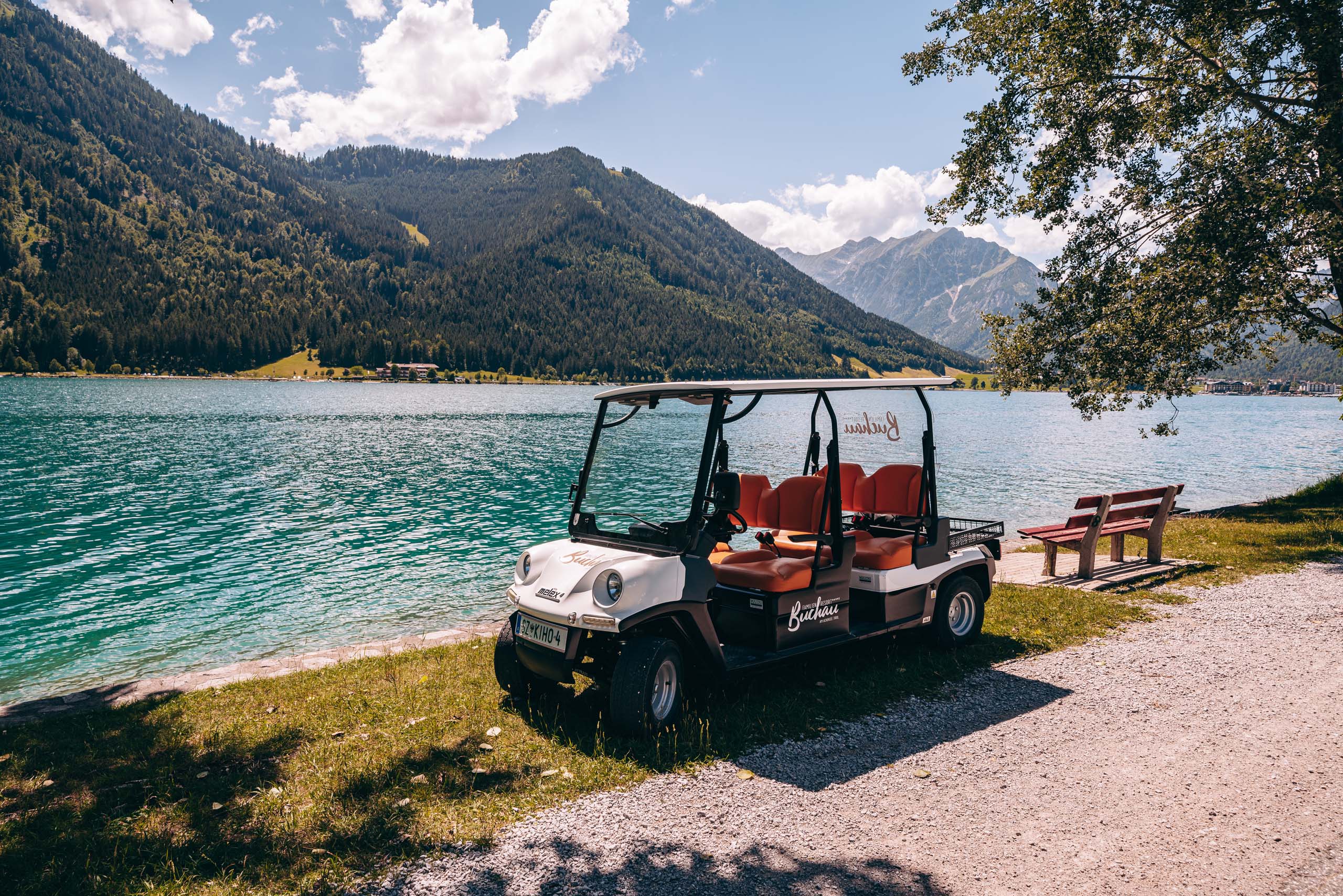 Wir lassen Bilder sprechen. Touristisches Elektrofahrzeug am Seeufer mit Bergpanorama im Hintergrund