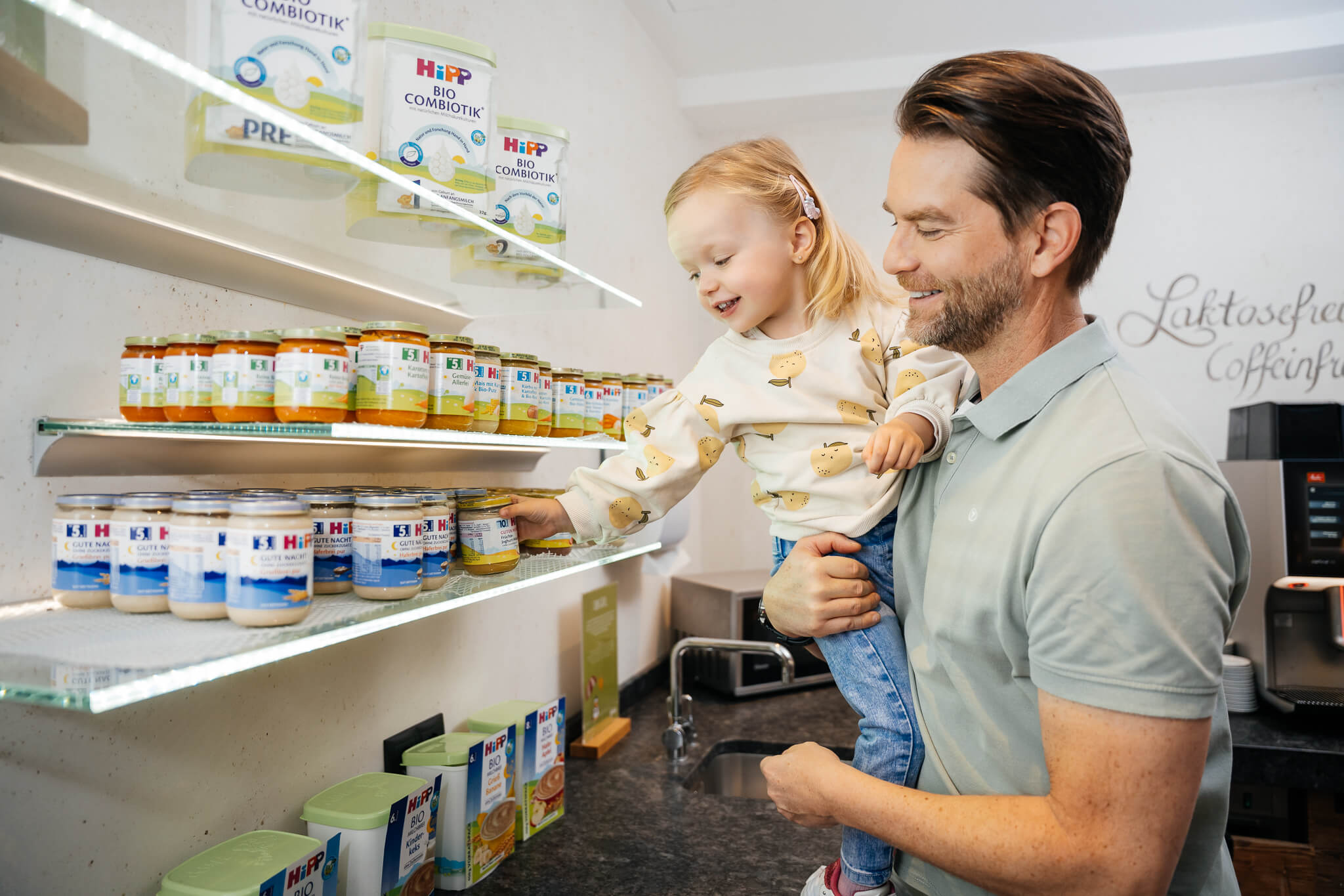Wir lassen Bilder sprechen. Mann hält Kind beim Auswählen von Babynahrung im Regal
