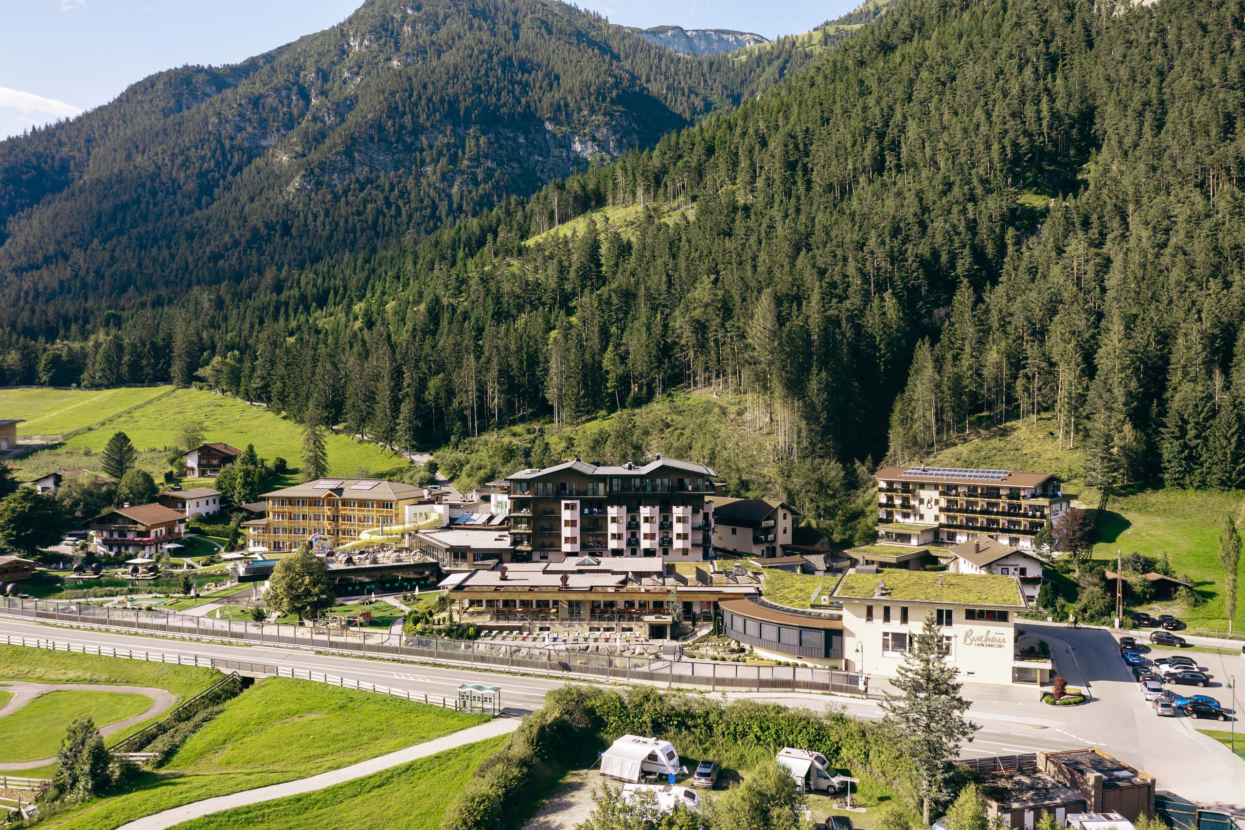 Wir lassen Bilder sprechen. Blick auf Hotelanlage mit Bergen und Wald im Hintergrund