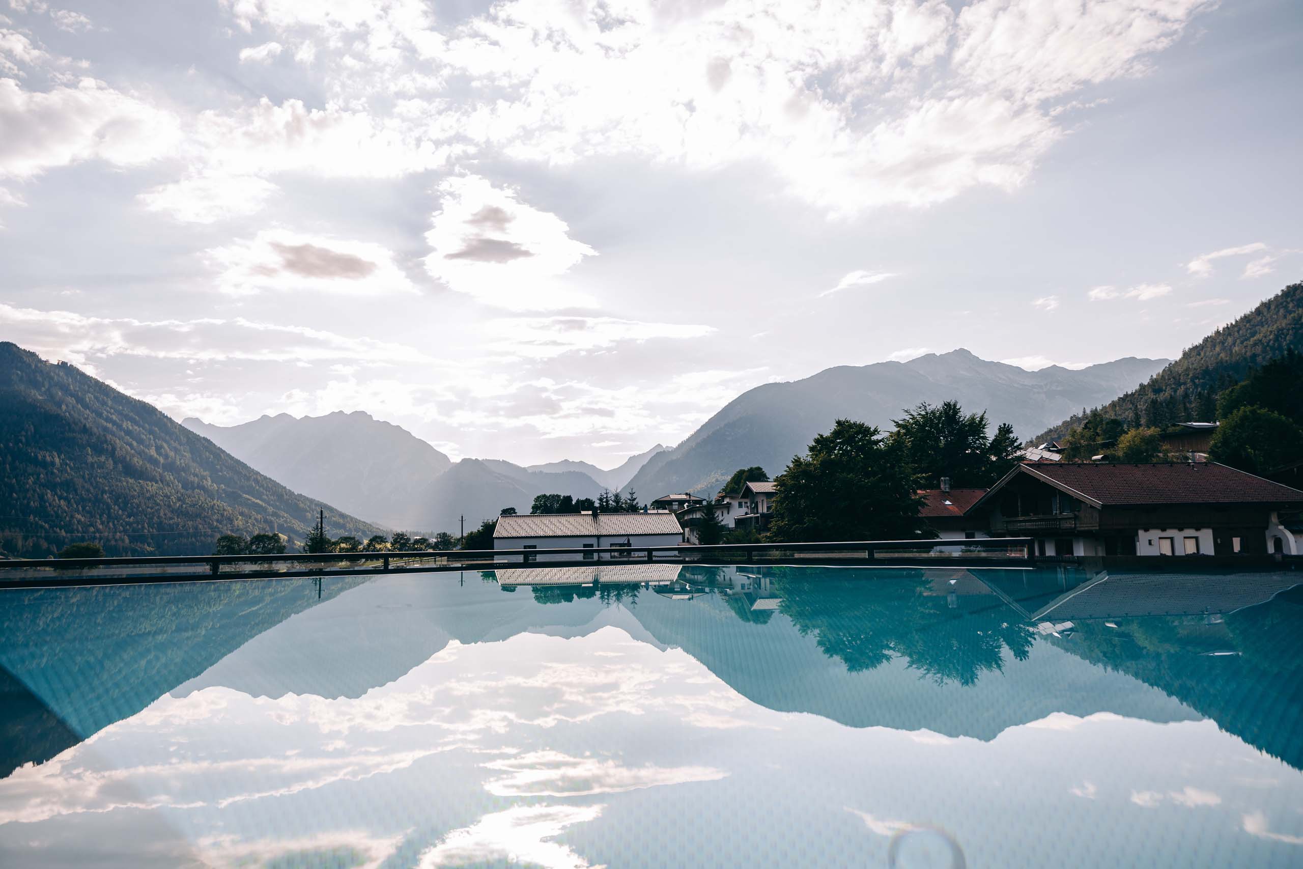 Wir lassen Bilder sprechen. Berglandschaft mit Häusern und Wasserbecken, das Himmel und Berge spiegelt