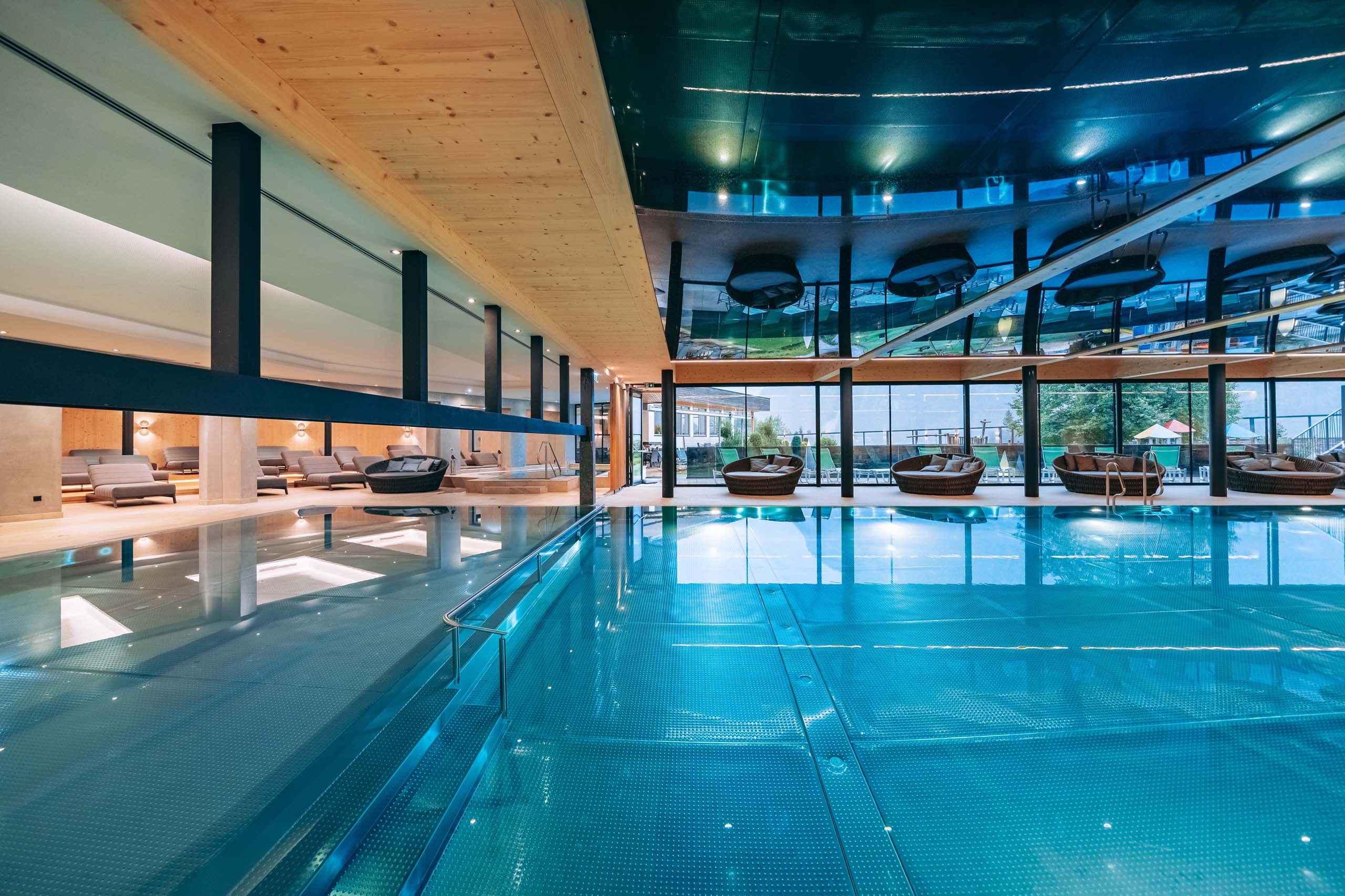 Wir lassen Bilder sprechen. Moderner Innenpool mit gemütlichen Liegen und großer Glasfront