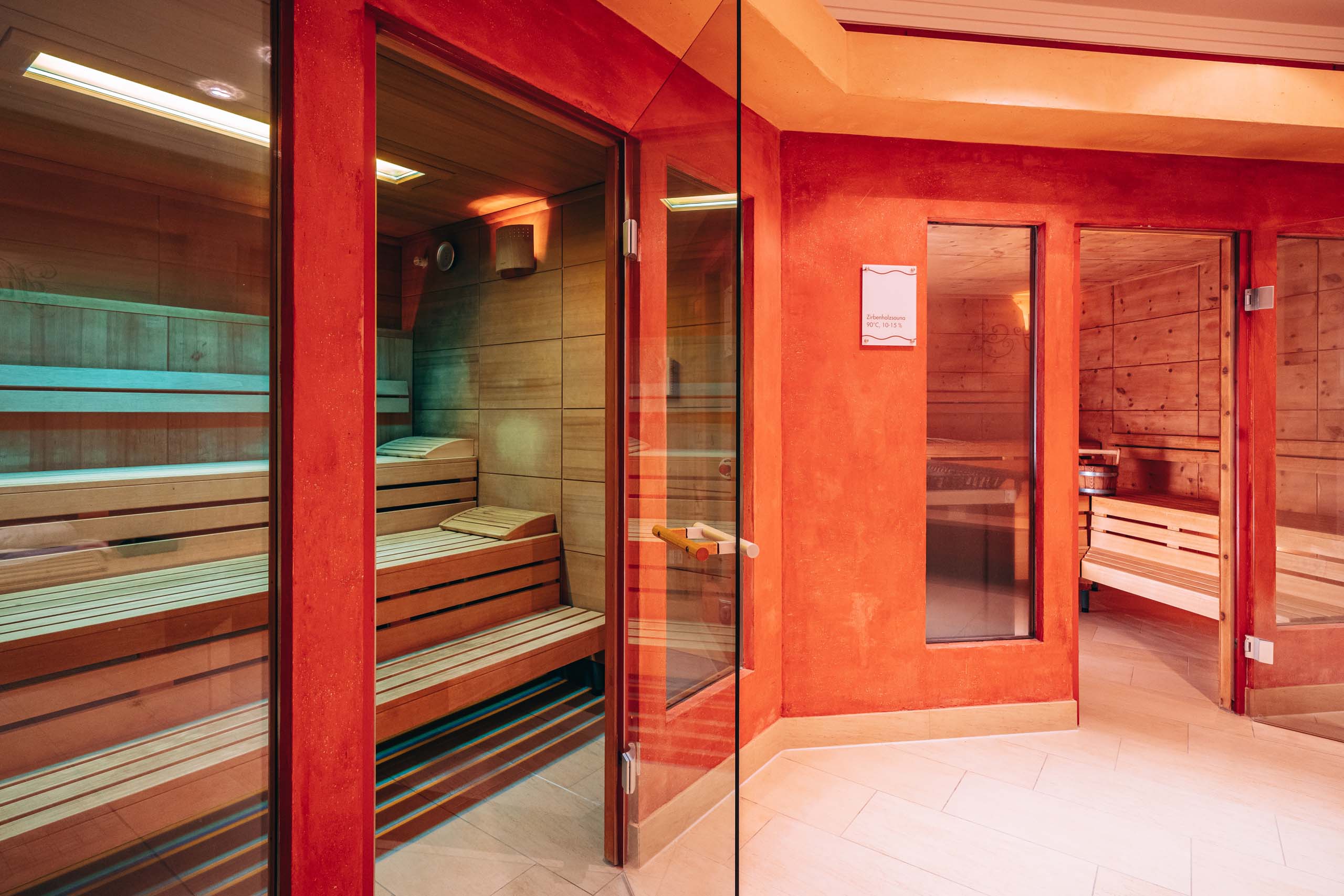 Wir lassen Bilder sprechen. Moderne Sauna mit Holzbänken und Glastüren in rotem Raum