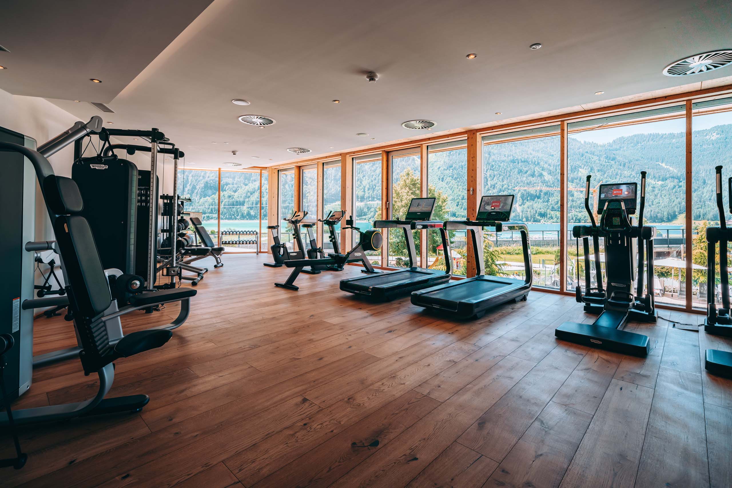 Wir lassen Bilder sprechen. Helles Fitnessstudio mit Geräten und großem Fenster mit Bergblick