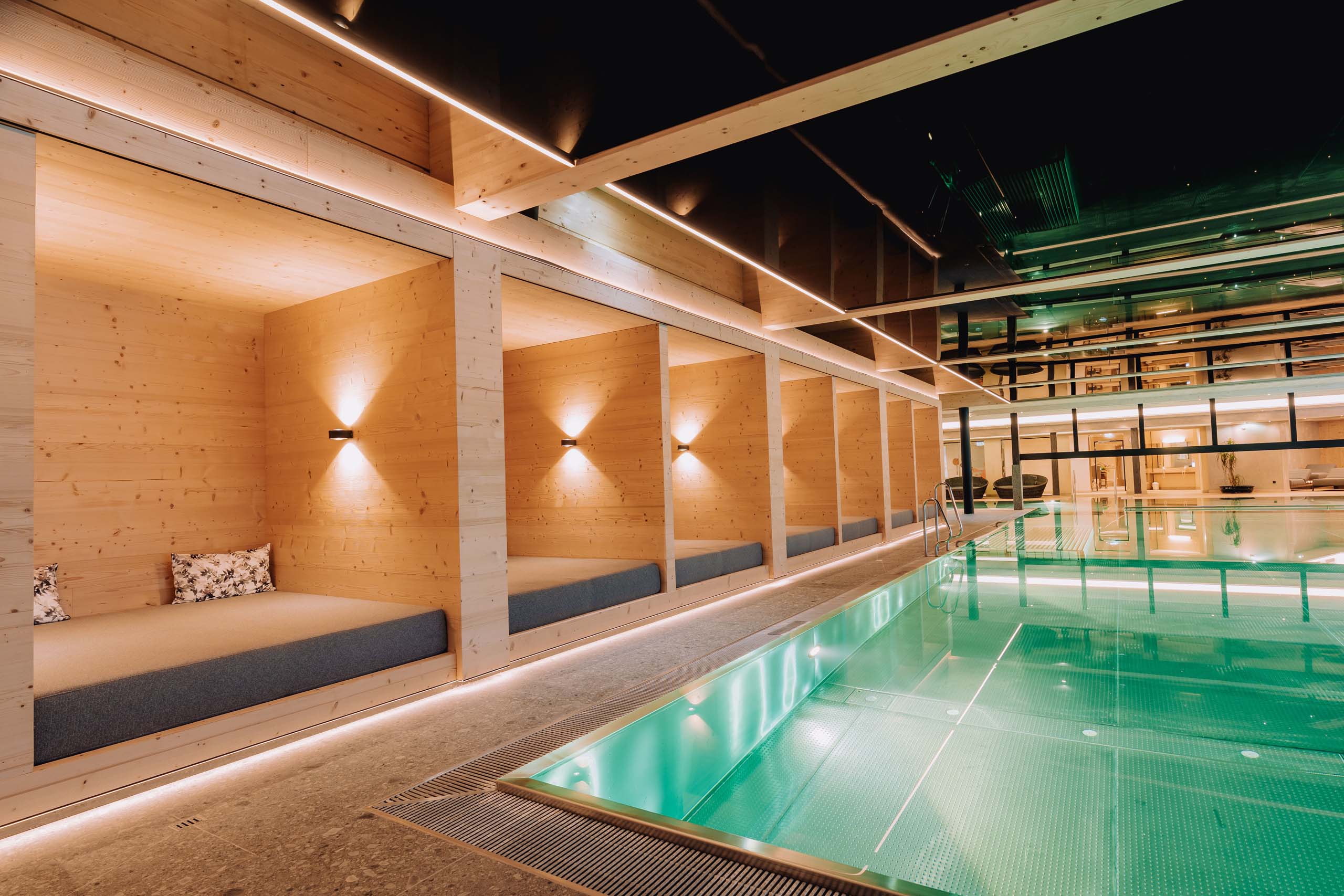 Wir lassen Bilder sprechen. Modernes Hallenbad mit Holzliegen und indirekter Beleuchtung