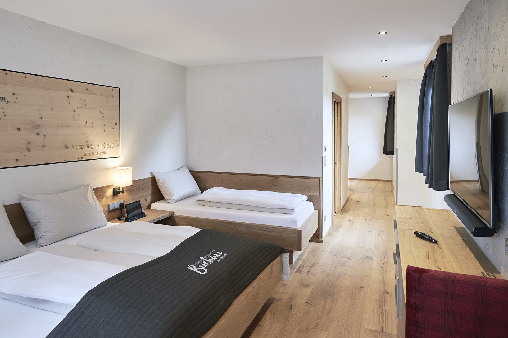 Zimmer und Angebote am Achensee Modernes Hotelzimmer mit zwei Betten, Fernseher und Holzmöbeln