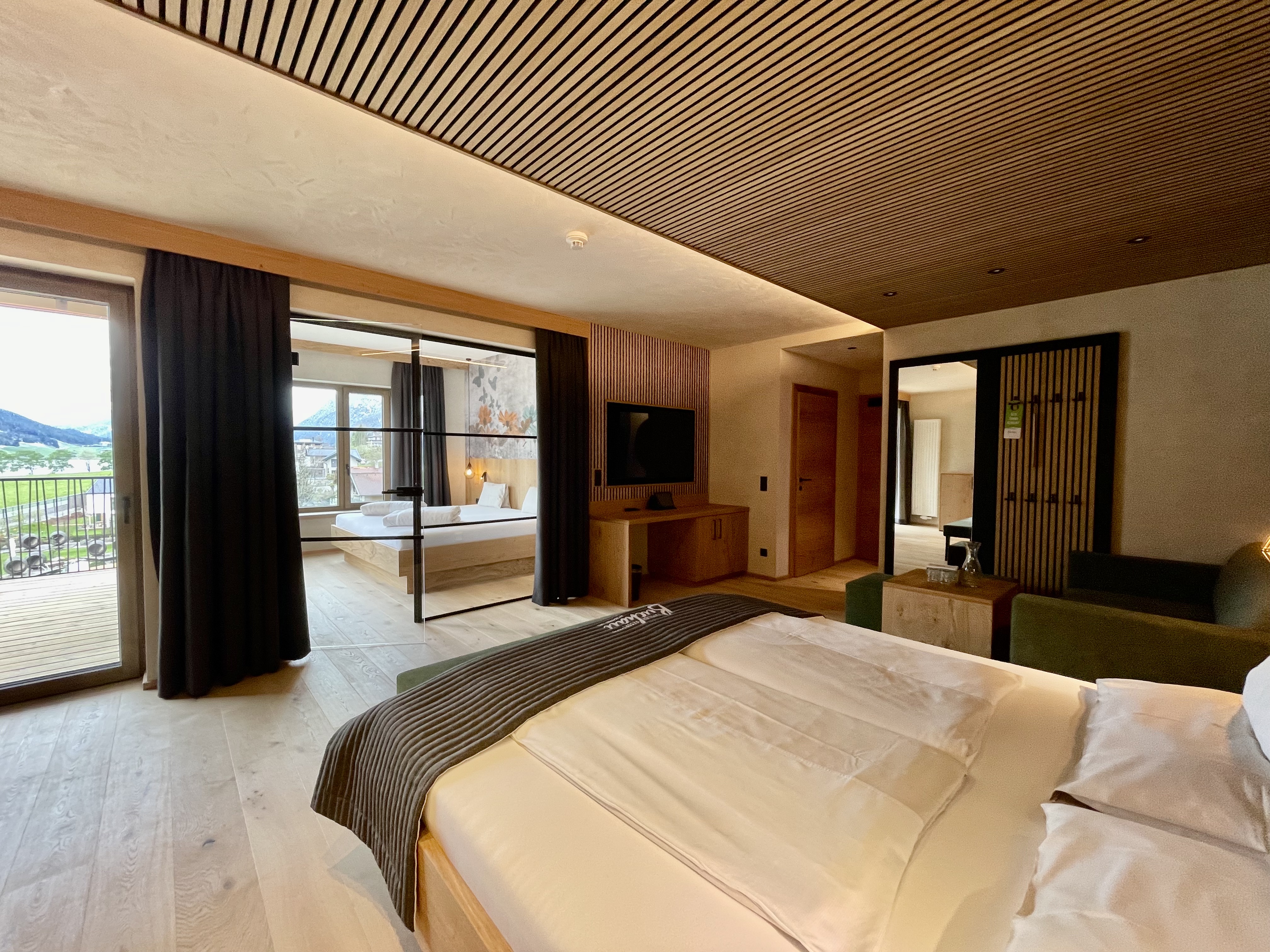 Wir lassen Bilder sprechen. Modernes Hotelzimmer mit Doppelbett, Fernseher, Balkon und Ausblick auf die Berge