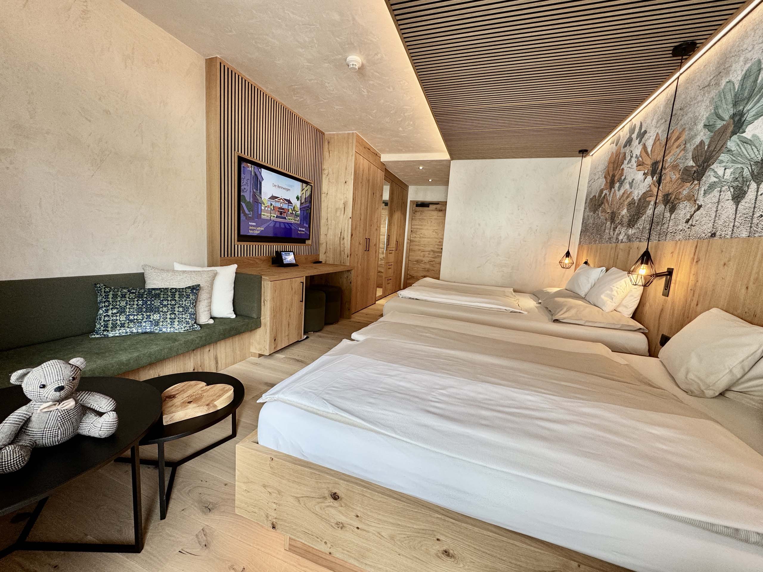 Wir lassen Bilder sprechen. Modernes Hotelzimmer mit zwei Betten, Sofa, Fernseher und Holzdekor