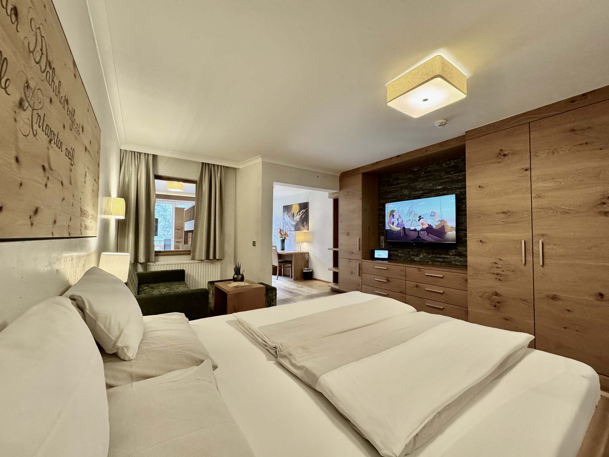 Wir lassen Bilder sprechen. Gemütliches Hotelzimmer mit Doppelbett, TV und Holzmöbeln