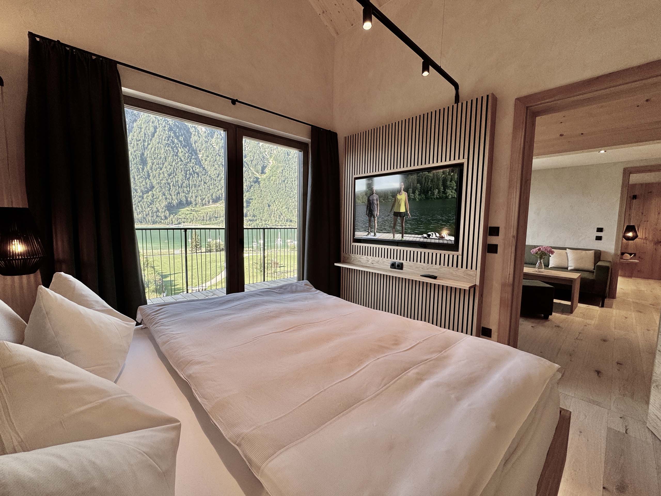 Wir lassen Bilder sprechen. Modernes Schlafzimmer mit Balkon, Bergblick und Fernseher an der Holzwand