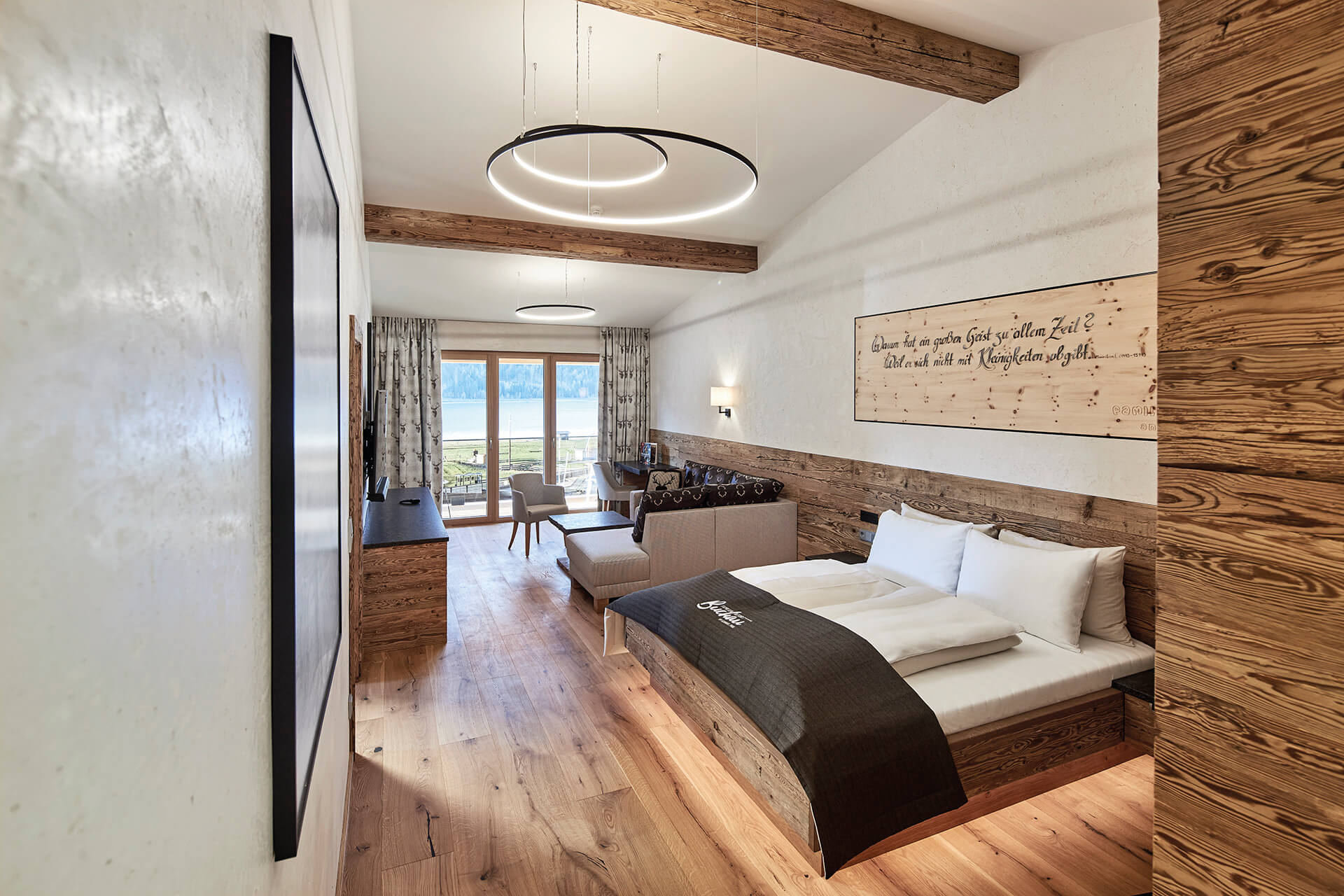 Wir lassen Bilder sprechen. Modernes Hotelzimmer mit Holzmöbeln und Blick auf See durch Fenster