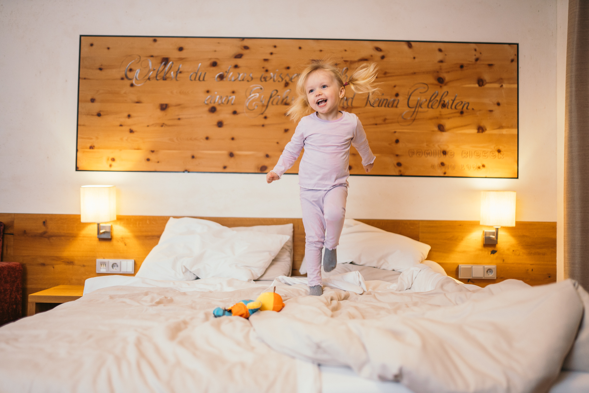 Wir lassen Bilder sprechen. Glückliches kleines Mädchen springt auf einem Bett in einem gemütlichen Schlafzimmer